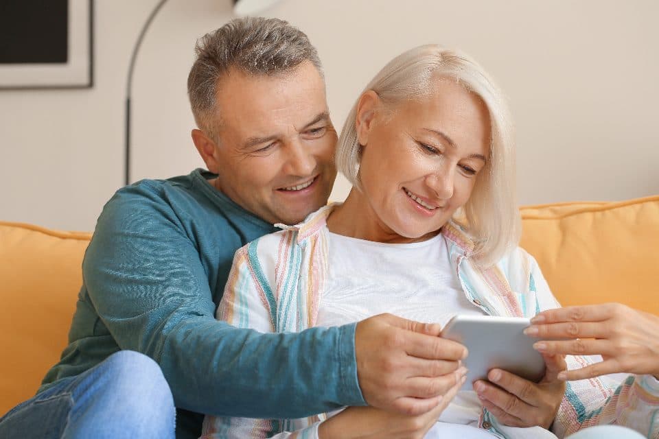 A couple sitting together on a sofa going through paperwork